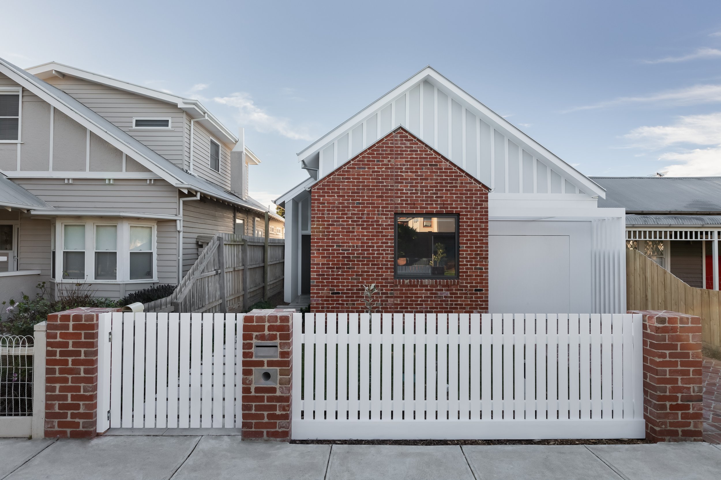 Knock down rebuild, Heritage overlay red brick and white wood clad building with picket fence - Melbourne Australia