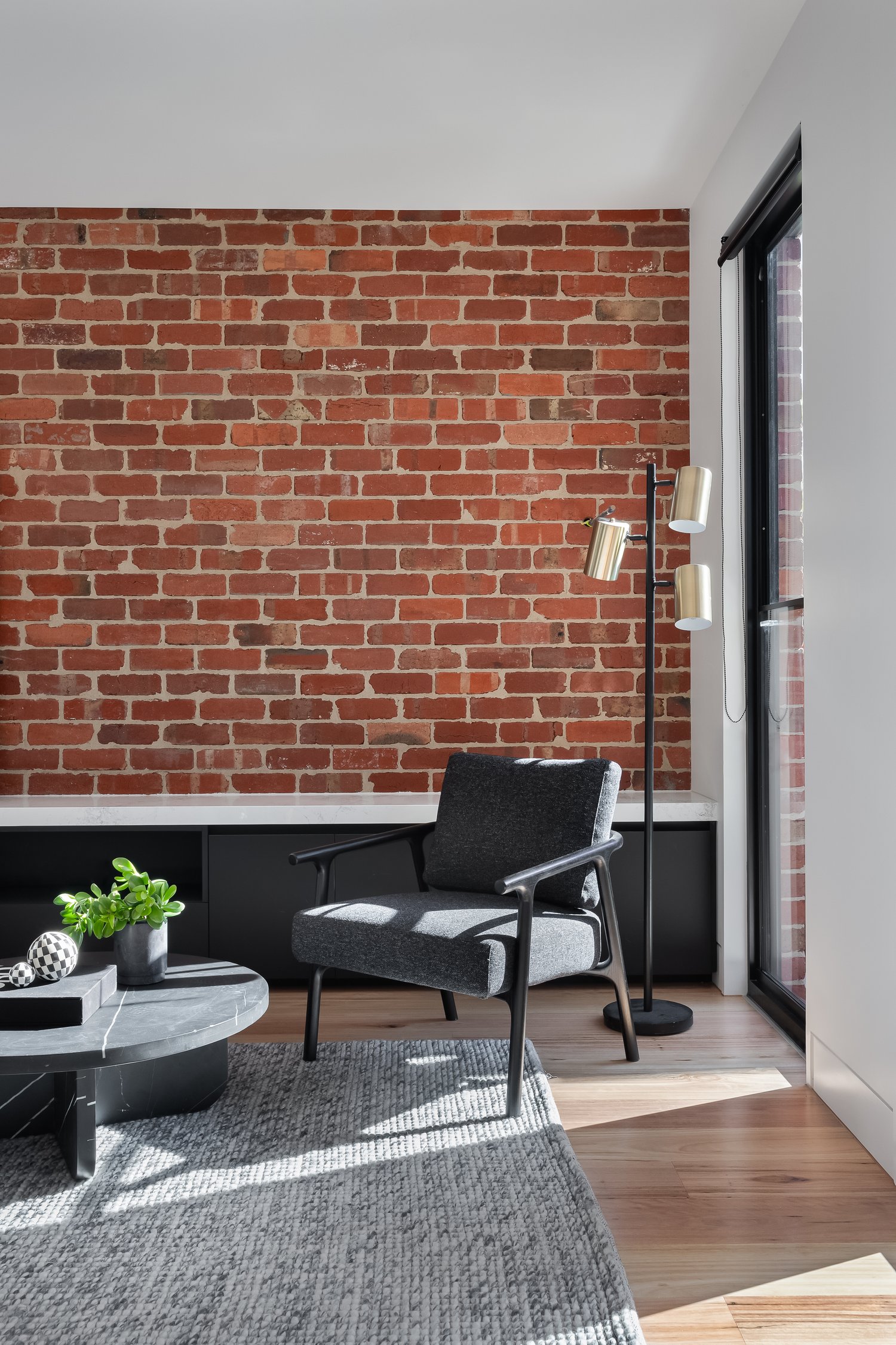 Red brick feature wall in living area with chair, knock down rebuild, Newport, Victoria, Barnes Matina